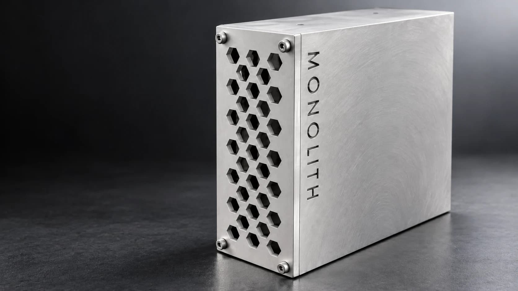 Close-up of Monolith’s brushed aluminium, honeycomb openings, corner fasteners and engraved lettering; concept render